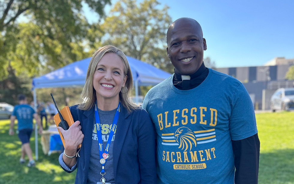 A woman and a priest wearing Blessed Sacrament School apparel