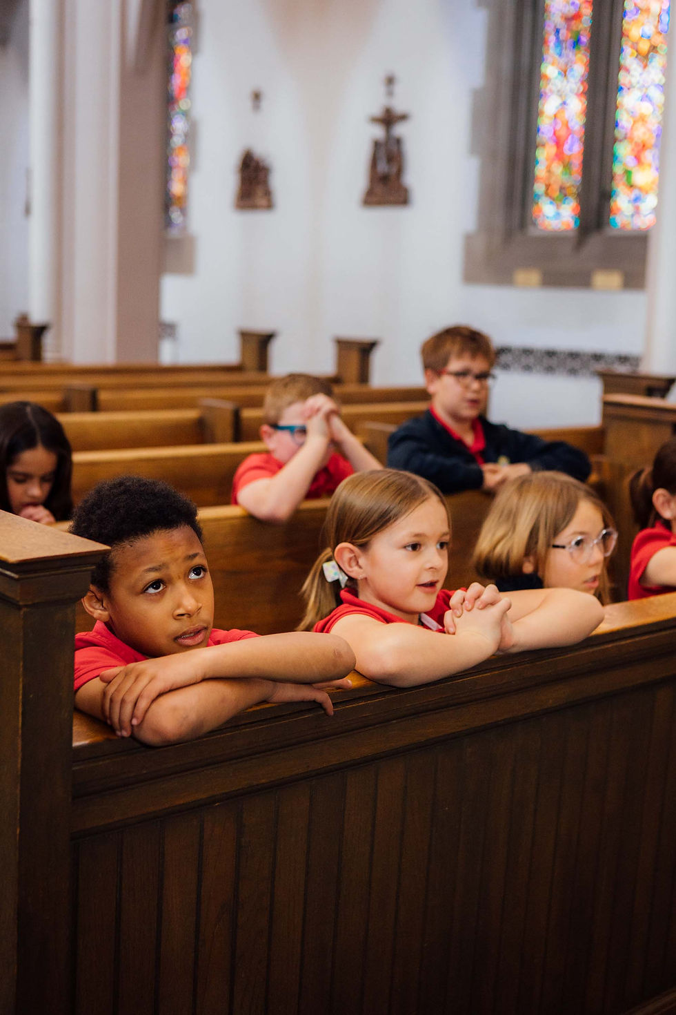 Kids in red uniforms kneeling in a Catholic church