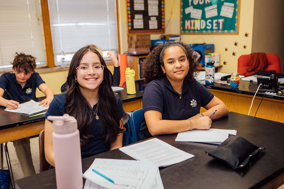 Two girls in navy blue uniforms smiling during class