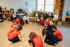Kids in red uniforms sitting in a circle with notecards playing a game