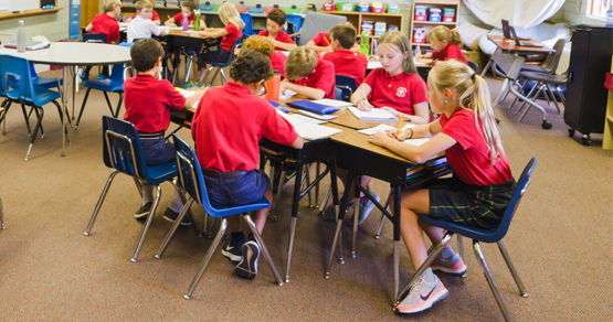 A group of students wearing red unifroms working on a group project