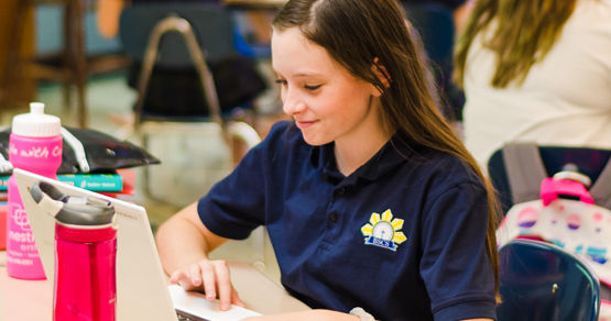 A middle school girl wearing a navy blue shirt working on a computer